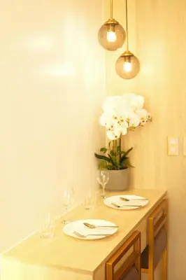a table with glasses and a vase with white flowers at Hotel Like Staycation 3 Makati with Amazing View in Manila