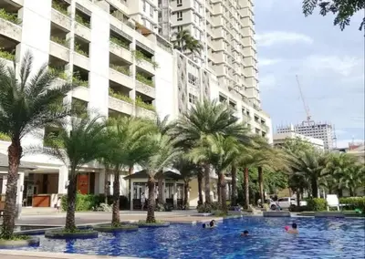 a pool with palm trees in front of a building at La verti 1BR Affordable staycation for family groups in Manila