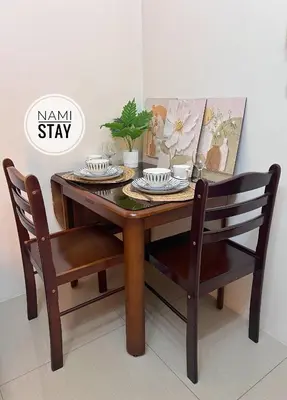 a dining room table with two chairs and a wooden table with two plates at Nami Stay at Shore Residences 1 in Manila