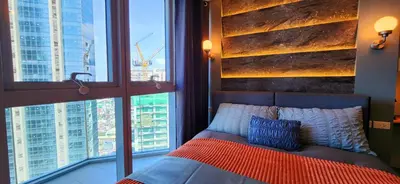 a bedroom with a bed with two pillows and two windows at BGC Family Suite Steps Away from Mall with FREE Parking with Washer Dryer in Manila