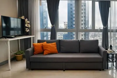 a gray couch with orange pillows in a living room at BGC Family Suite Steps Away from Mall with FREE Parking with Washer Dryer in Manila