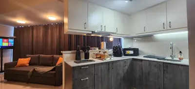 a kitchen with white cabinets and a couch and a chair at BGC Family Suite Steps Away from Mall with FREE Parking with Washer Dryer in Manila