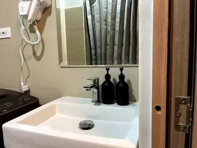 a bathroom sink with a mirror and two bottles on it at Cozy Minimalist Condo unit in Manila