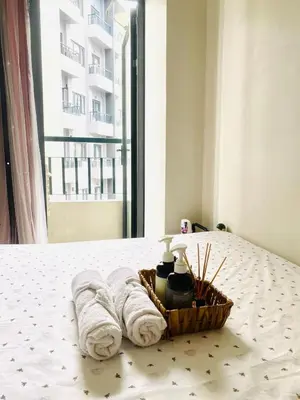 a basket of towels on a bed with a window at Staycation 15 minutes from NAIA with Massage Chair in Manila