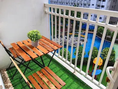 a wooden bench sitting on a balcony with a view of a pool at SLY Staycation at Shore Residences Mall of Asia in Manila