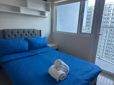 a bedroom with a blue bed with a towel on it at Bright & Cozy 1 BR in Jazz Residences Tower B in Manila