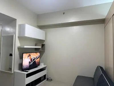 a living room with a flat screen tv in a room at Bright & Cozy 1 BR in Jazz Residences Tower B in Manila