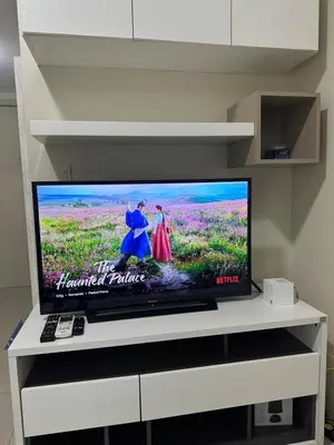 a flat screen tv sitting on a white tv stand at Bright & Cozy 1 BR in Jazz Residences Tower B in Manila