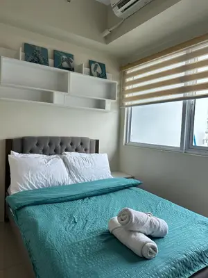 a bedroom with a bed with towels on it at Bright & Cozy 1 BR in Jazz Residences Tower B in Manila