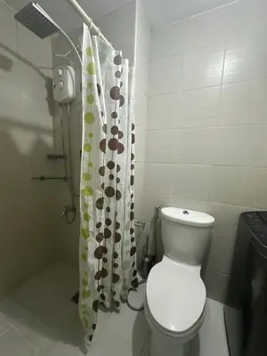 a bathroom with a toilet and a shower curtain at Bright & Cozy 1 BR in Jazz Residences Tower B in Manila