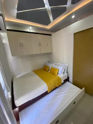 a small bedroom with a bed with a yellow blanket at MGS Suite Shore 2 Residences in Manila