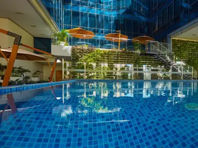 a large swimming pool with umbrellas in a building at Stay Across NAIA Terminal 3 in Newport City in Manila