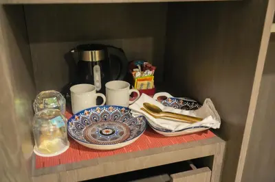 a shelf with plates and cups and a coffee maker at Stay Across NAIA Terminal 3 in Newport City in Manila