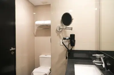 a bathroom with a toilet and a phone on the wall at Stay Across NAIA Terminal 3 in Newport City in Manila
