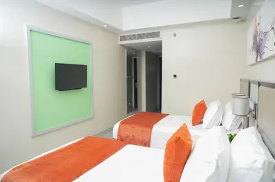 two beds in a room with a tv on the wall at Stay Across NAIA Terminal 3 in Newport City in Manila