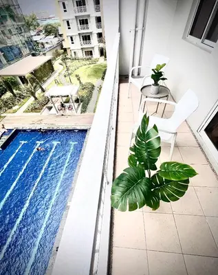 a balcony with a swimming pool and a table and chairs at Angels Place The Atherton, Manila Condo Near Airport in Manila