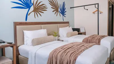 two beds in a hotel room with a mural on the wall at City Getaway in the Heart of Entertainment City in Manila