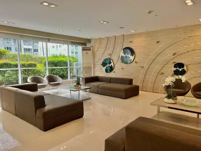 a living room with couches and tables and a wall of windows at Studio Condo by Sea Residences near MOA 02 in Manila