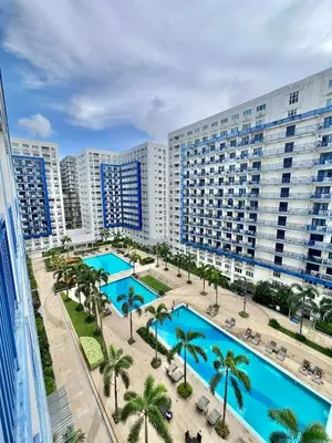 an aerial view of a resort with two pools and palm trees at Studio Condo by Sea Residences near MOA 02 in Manila