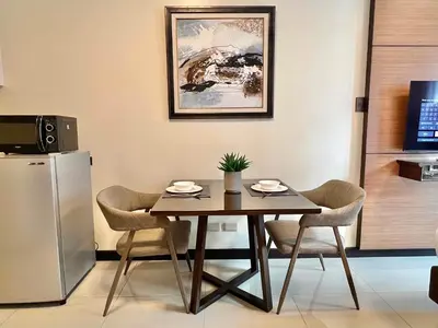 a dining room table with chairs and a refrigerator at Studio Condo by Sea Residences near MOA 02 in Manila