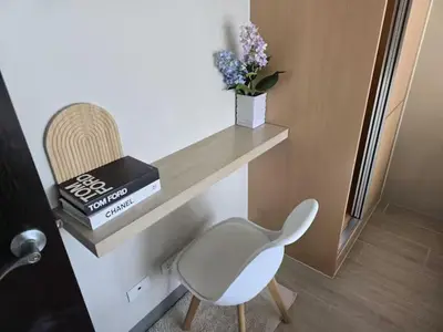 a white chair sitting next to a shelf with books at Modern Comfort & Snap Worthy with Pool, Gym & More in Manila