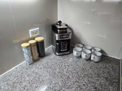 a coffee maker and four cups on a counter at Modern Comfort & Snap Worthy with Pool, Gym & More in Manila