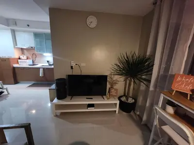 a living room with a flat screen tv on a stand at Cozy 1BR Corner with Panoramic City Skyline View in Manila