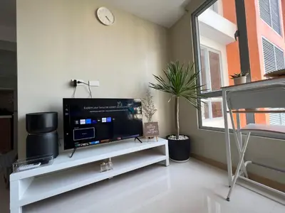 a living room with a flat screen tv on a white shelf at Cozy 1BR Corner with Panoramic City Skyline View in Manila
