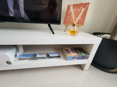 a white shelf with books and a tv on it at Cozy 1BR Corner with Panoramic City Skyline View in Manila