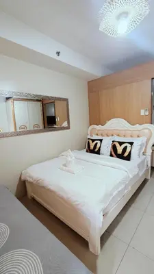 a bedroom with a large white bed with black and white pillows at Shell Residences MOA - Josh staycation in Manila
