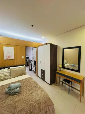 a bedroom with a bed and a desk and a mirror at Shell Residences MOA - Josh staycation in Manila