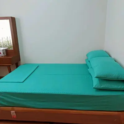 a bed with green sheets and pillows in a room at Short stay near NAIA in Manila