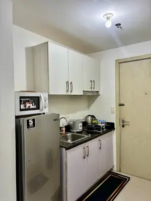 a kitchen with white cabinets and a stainless steel refrigerator at Resort-Style Living in Makati in Manila
