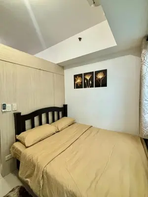 a bed in a bedroom with two pictures on the wall at Resort-Style Living in Makati in Manila
