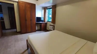 a bedroom with a bed and a desk and a window at Peaceful 2BR Home in Paranaque Airport Area in Manila