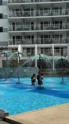 two people standing in a swimming pool in a building at Spacious Condo at Shell Residences, MOA Pasay - The Urban Stay in Manila