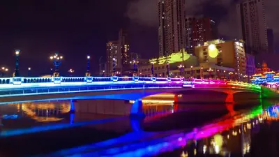 a bridge with colorful lights over a river at night at Private Rooms in Historic Manila Chinatown in Manila