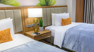 a hotel room with two beds and a table with a lamp at Business & Leisure Stay in Eastwood City in Manila