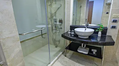 a bathroom with a sink and a glass shower at Business & Leisure Stay in Eastwood City in Manila