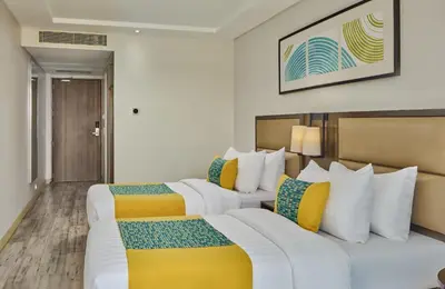 two beds in a hotel room with yellow and white at Sea View older in Manila