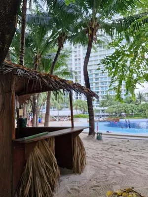 a bench on a beach with trees and a building at 15 Mins Away from NAIA Perfect for Staycation in Manila