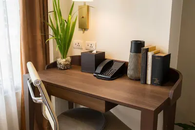 a wooden desk with a telephone and books on it at Modern City Stay Near Manila Bay Attractions in Manila