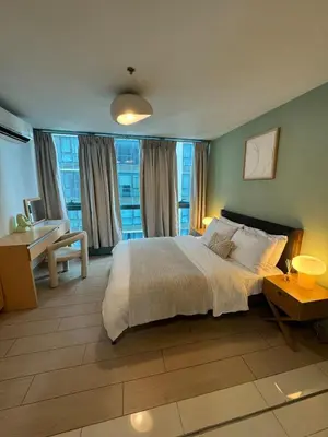 a bedroom with a bed and a desk and windows at Modern Nordic 1BR Big Queen Bed Uptown BGC in Manila