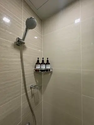 a shower in a bathroom with three bottles of soap at Modern Nordic 1BR Big Queen Bed Uptown BGC in Manila