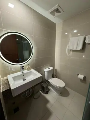 a bathroom with a toilet and a sink and a mirror at Modern Nordic 1BR Big Queen Bed Uptown BGC in Manila
