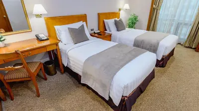 a hotel room with two beds and a desk at Ortigas CBD Near Business & Shopping Hubs in Manila
