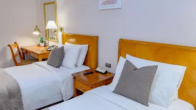 a hotel room with two beds and a desk at Ortigas CBD Near Business & Shopping Hubs in Manila