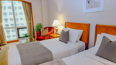 a hotel room with two beds and a red chair at Ortigas CBD Near Business & Shopping Hubs in Manila