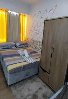 a bedroom with a bed and a wooden cabinet at Alabang Staycation By Renz in Manila