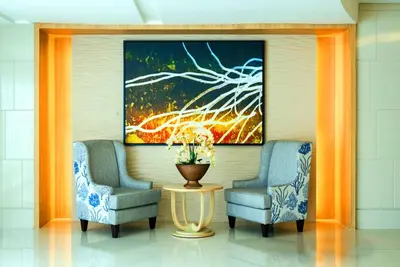 two chairs and a table in a lobby with a painting at Urban Retreat at Shell Residences with Netflix 300mbps Wifi in Manila
